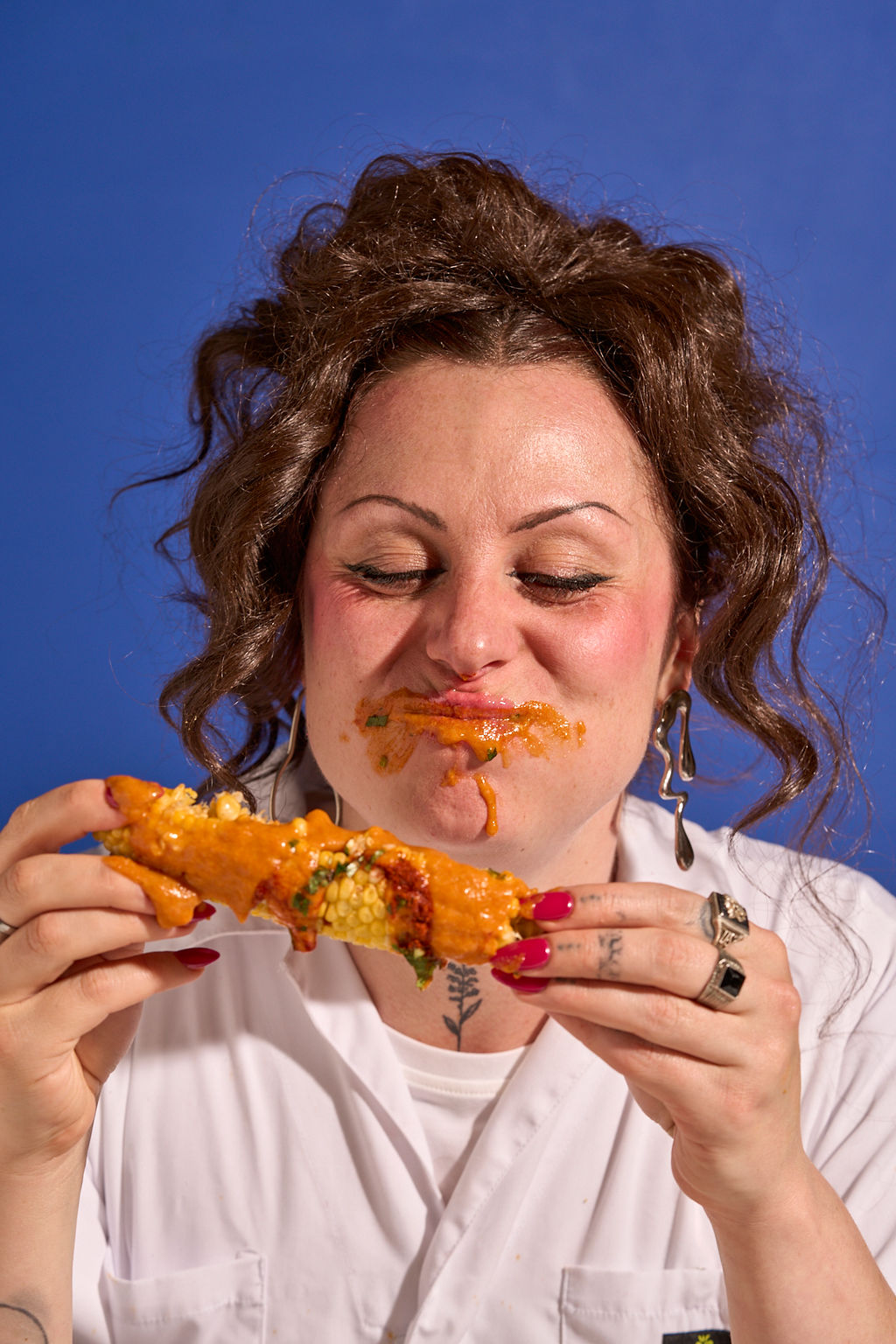 Eating Tikka-sauced corn against a cobalt wall