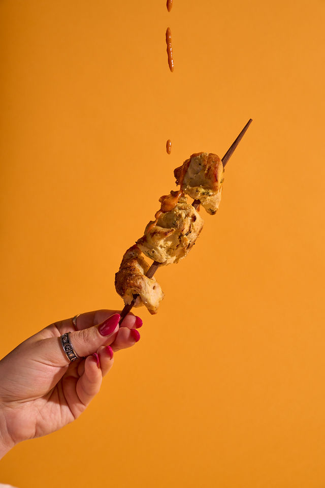 A Tikka skewer tossed against a marigold backdrop