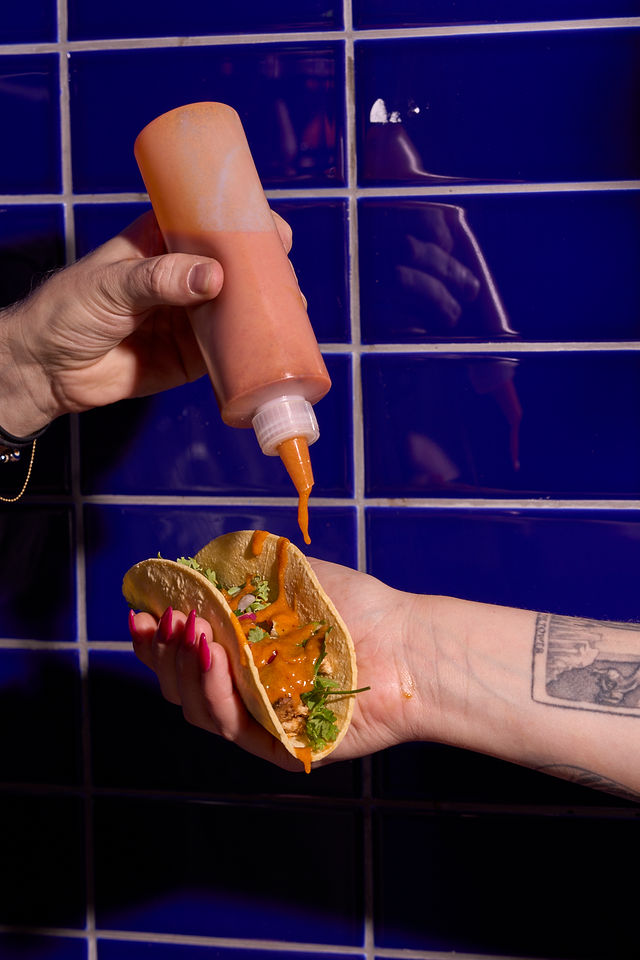 Sauce squeezed onto a taco against blue tile